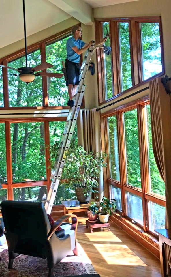 Window Doctor on ladder cleaning window